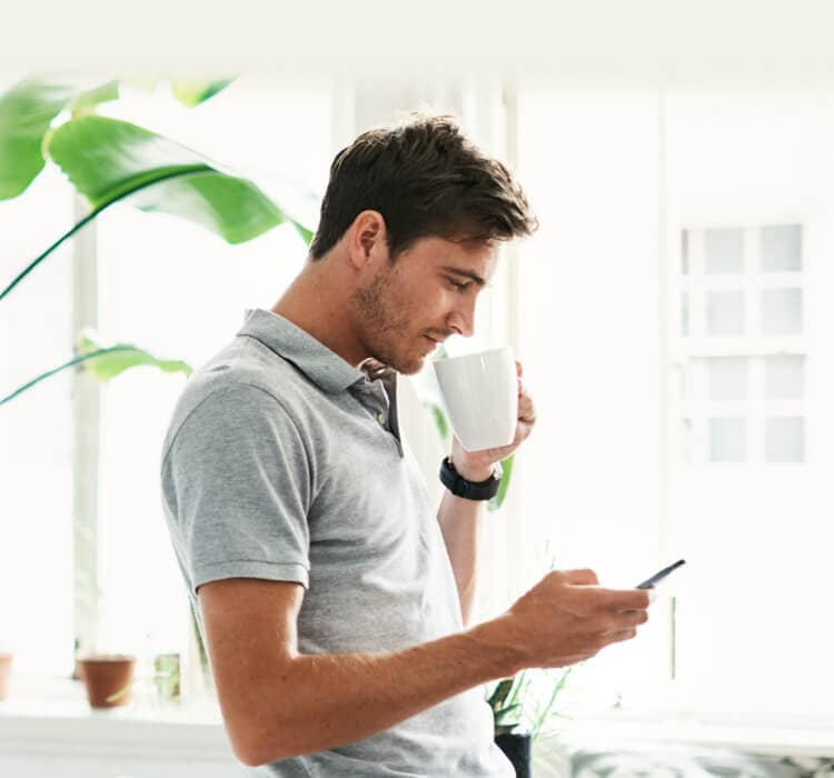 Uomo che beve del caffè tenendo in mano uno smartphone