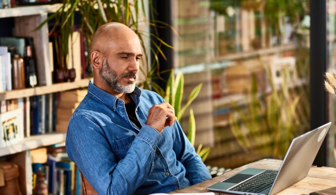 Uomo seduto alla scrivania che guarda un computer portatile