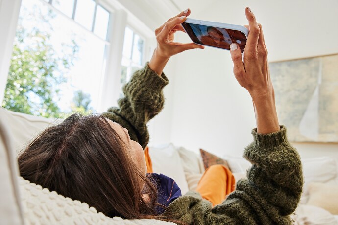 Donna sdraiata che guarda un telefono cellulare